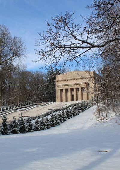 Wide steps in snowy landscape lead to columned stone monument on hill