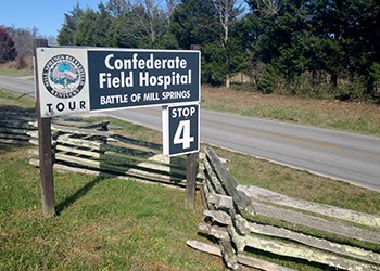 Battle Tour sign for stop 4 next to fence with road behind