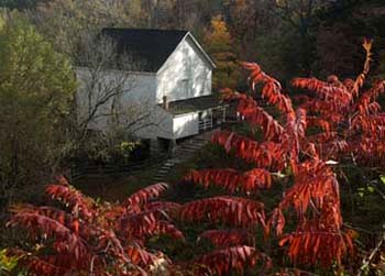 Bright fall foliage surrounds historic building with mill wheel