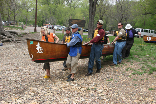 People carry a canoe to the river. People carry a canoe to the river.