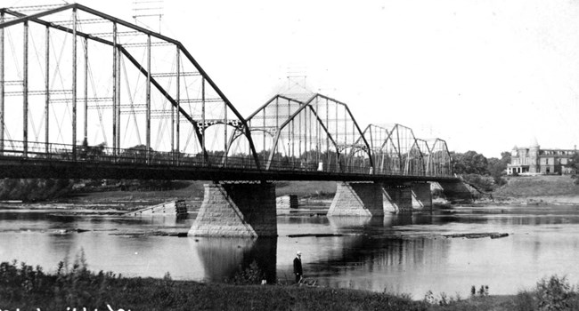 A steel bridge spans a large river.