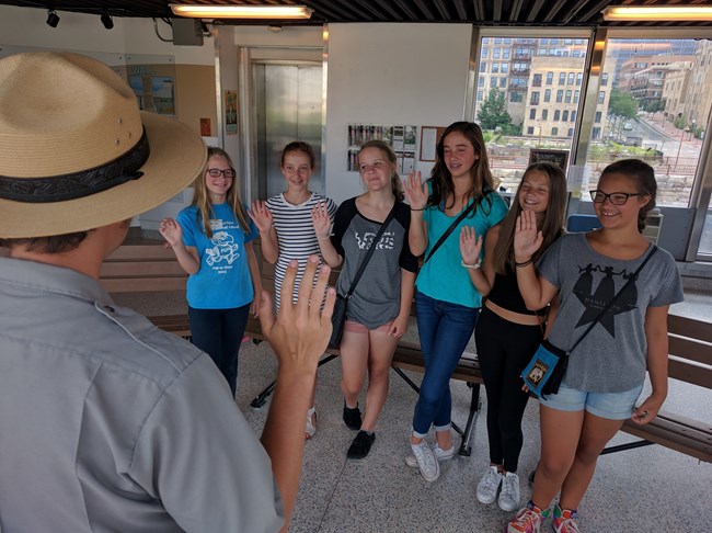 A park ranger swears in multiple junior rangers at the St. Anthony Falls Center A park ranger swears in multiple junior rangers at the St. Anthony Falls Center