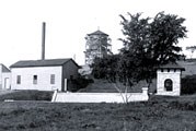 Buildings sit beside Coldwater Spring in this black and white photograph.