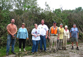 People standing in front of a large pile of cut buckthorn. People standing in front of a large pile of cut buckthorn.