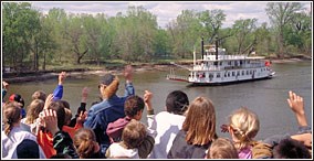 Students waving to a paddleboat running upriver.