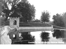 A black and white photograph with the reservoir and spring house surrounded by lawns and trees.
