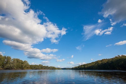 A large river runs between forest-covered shorelines.