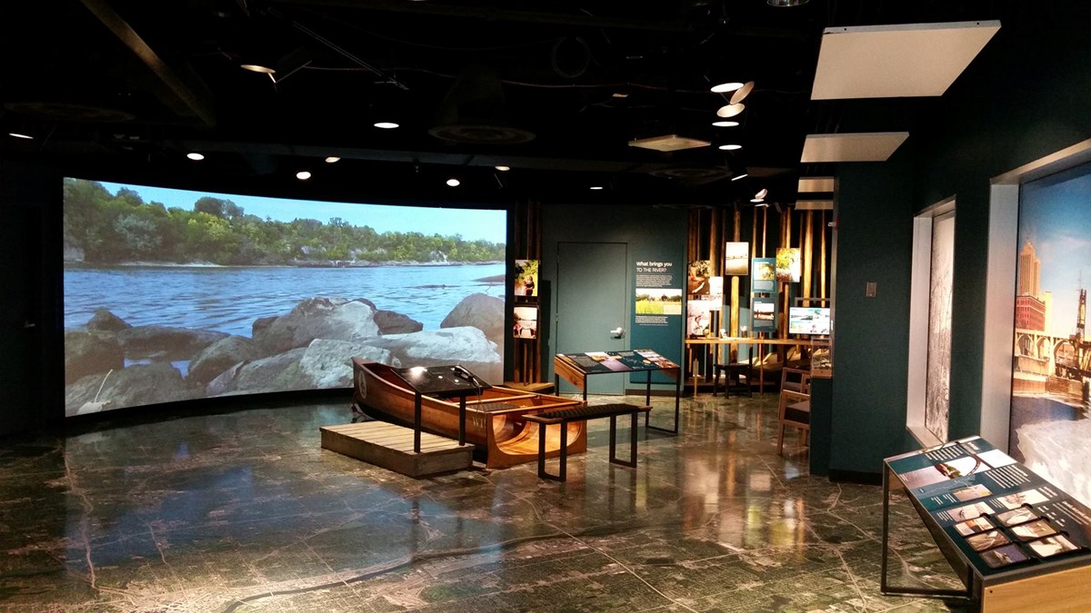 A visitor center with a canoe in front of a screen showing the river.