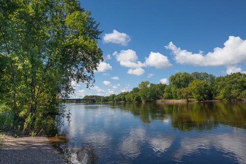 A large river flows through wooded shorelines.