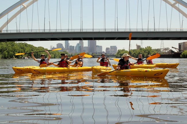 A group of kayakers paddling under the Lowry Bridge