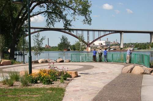 People watching a river from a city park.