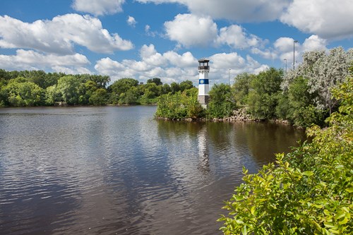 In the distance a lighthouse looks over the Mississippi River in the foreground.