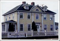 Large two story yellow house with a white picket fence