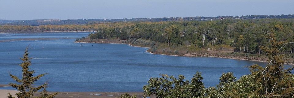 The Missouri River View downriver showing sandbars and green trees.