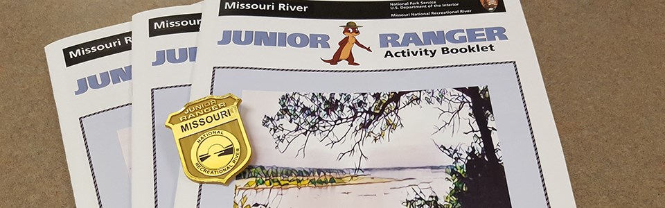 Cover view of three junior ranger booklets with a gold junior ranger badge.