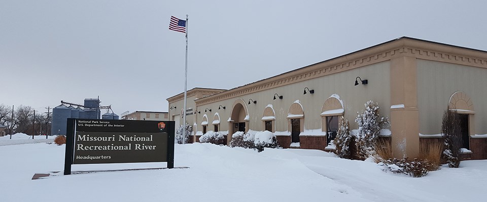 Outdoor winter scene of park headquarters building in snow. Sky above is gray.