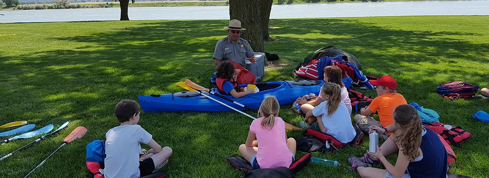 A National Park Service ranger talks to a group of kids about kayak use on the river.