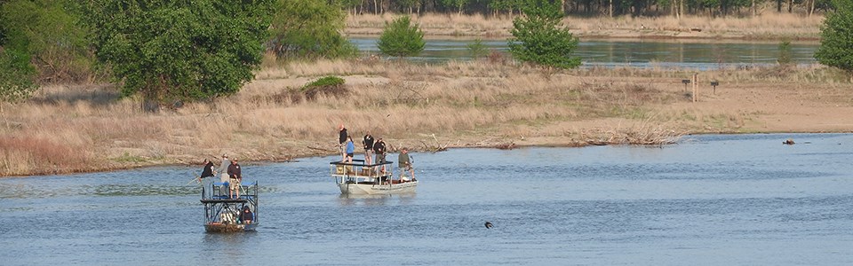 Anglers in boats bowfishing the river.