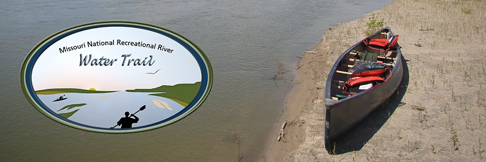 An empty canoe on a river beach. The logo for the MNRR Water Trail is on the left of picture.