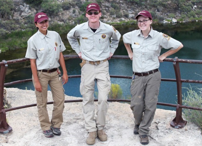 Three youth stand in volunteer uniforms and hats. Three youth stand in volunteer uniforms and hats.