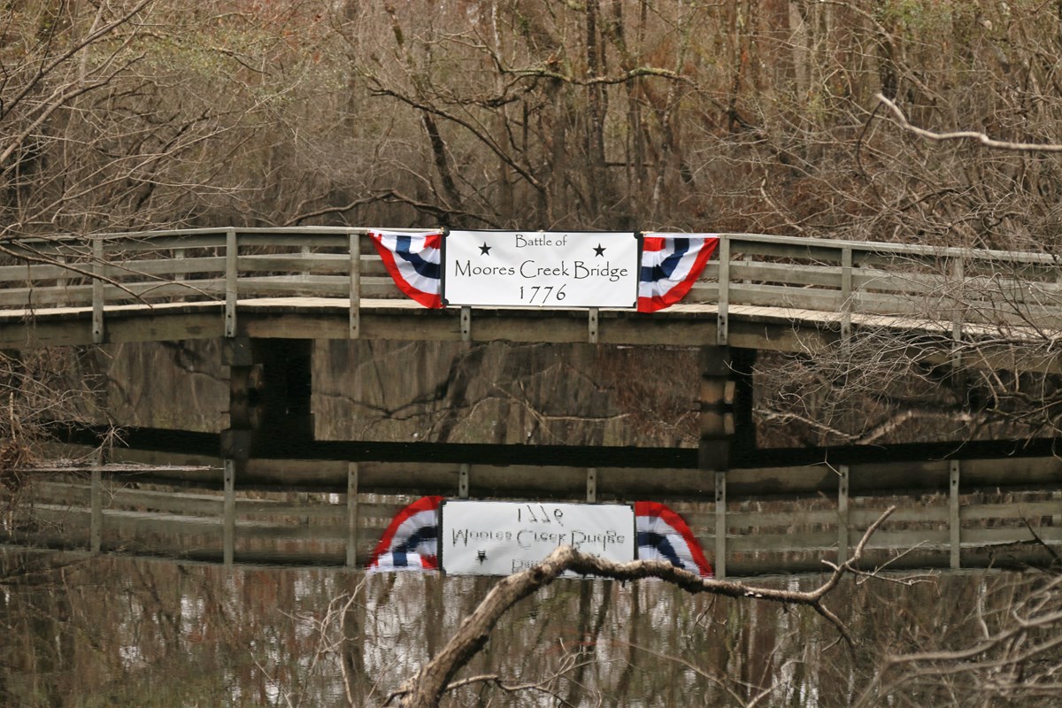 White Banner hanging on a wooden bridge