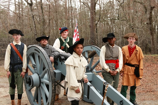 Diverse Group of Volunteers around a Cannon