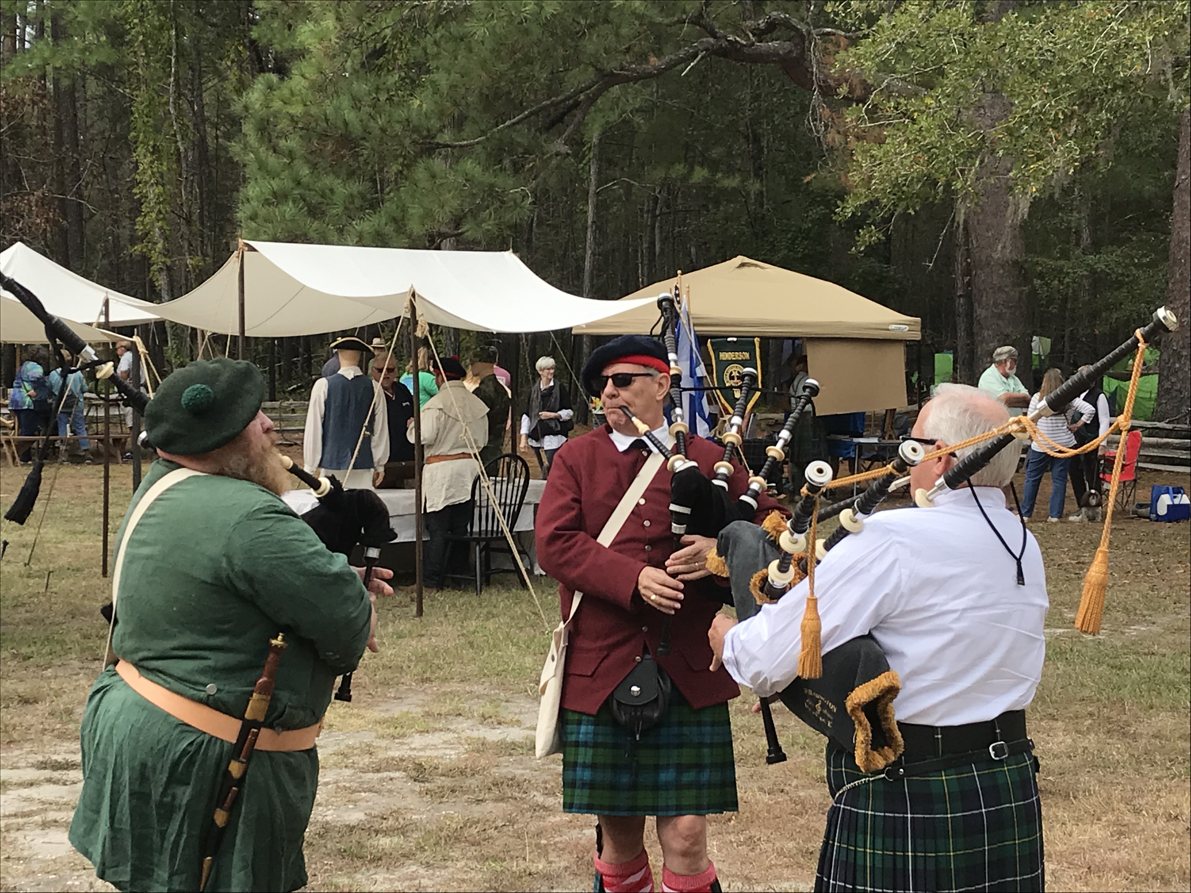 Three men in Scottish clothing playing bagpipes