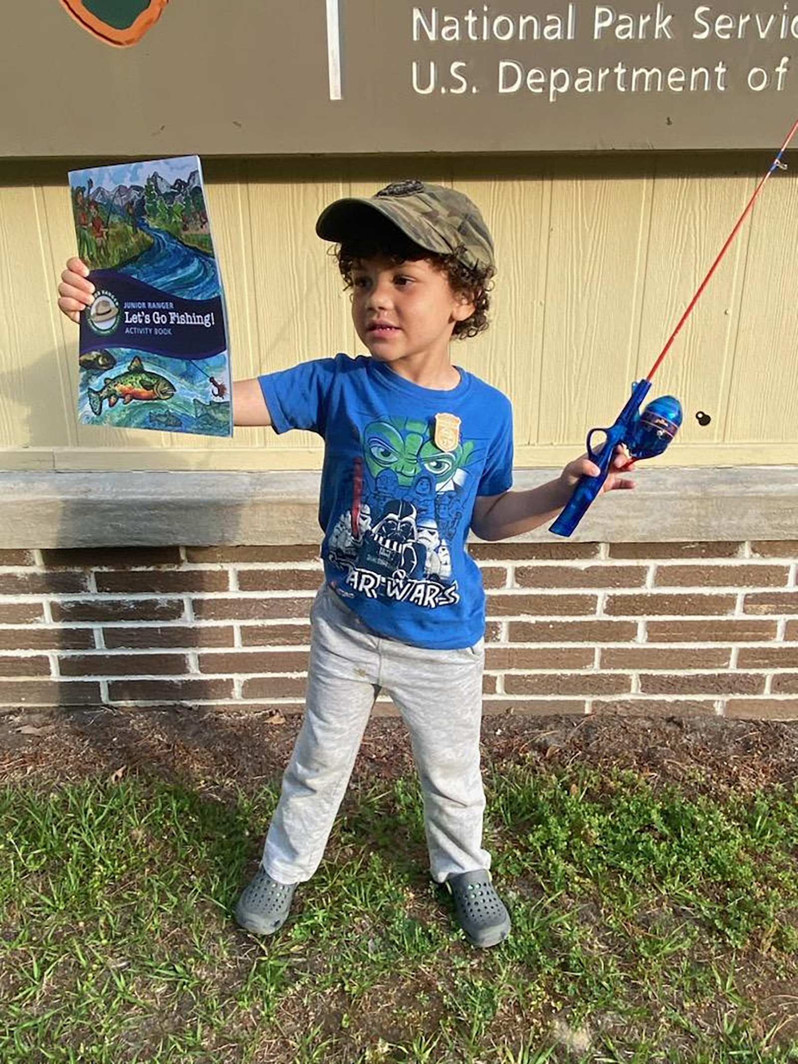 Young visitor holding fishing pole and Junior Ranger Angler booklet