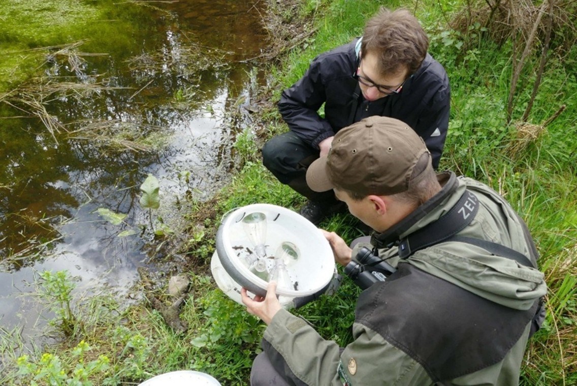 Two Men gathering samples by water.
