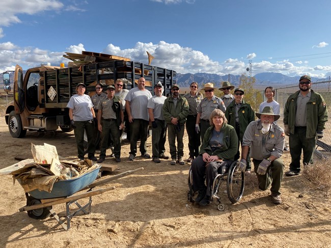 A group of employees pose for a group shot while clearing out debris from an area of the preserve