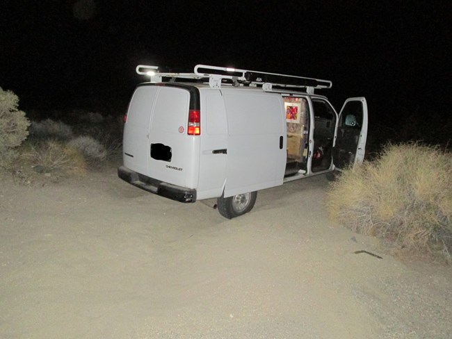 A white van stuck in a rut after dark