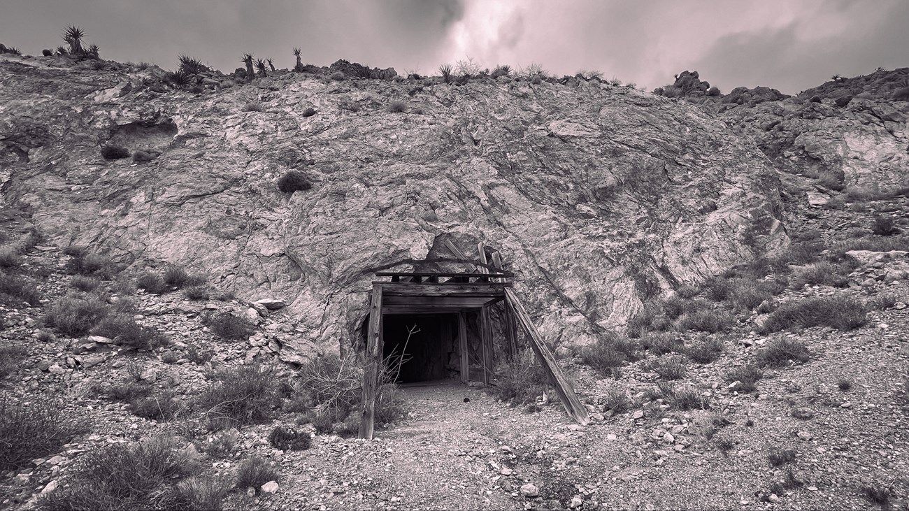 a black and white photo of a mine adit in the desert