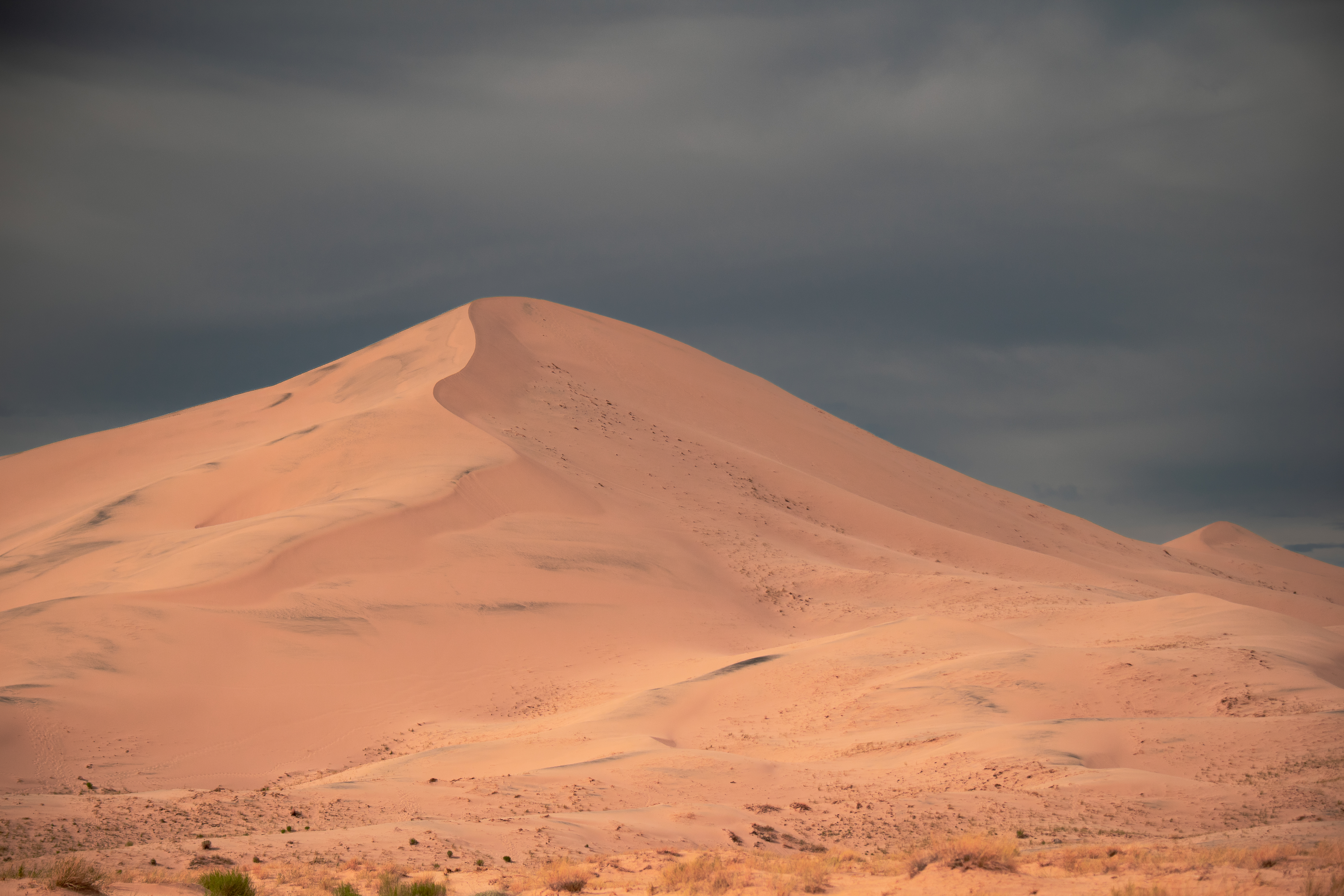 A sking large sand dune stands out against a cloudy sky