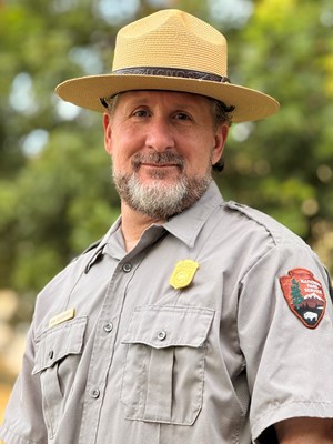 a man in a grey uniform shirt and a straw flat brimmed hat