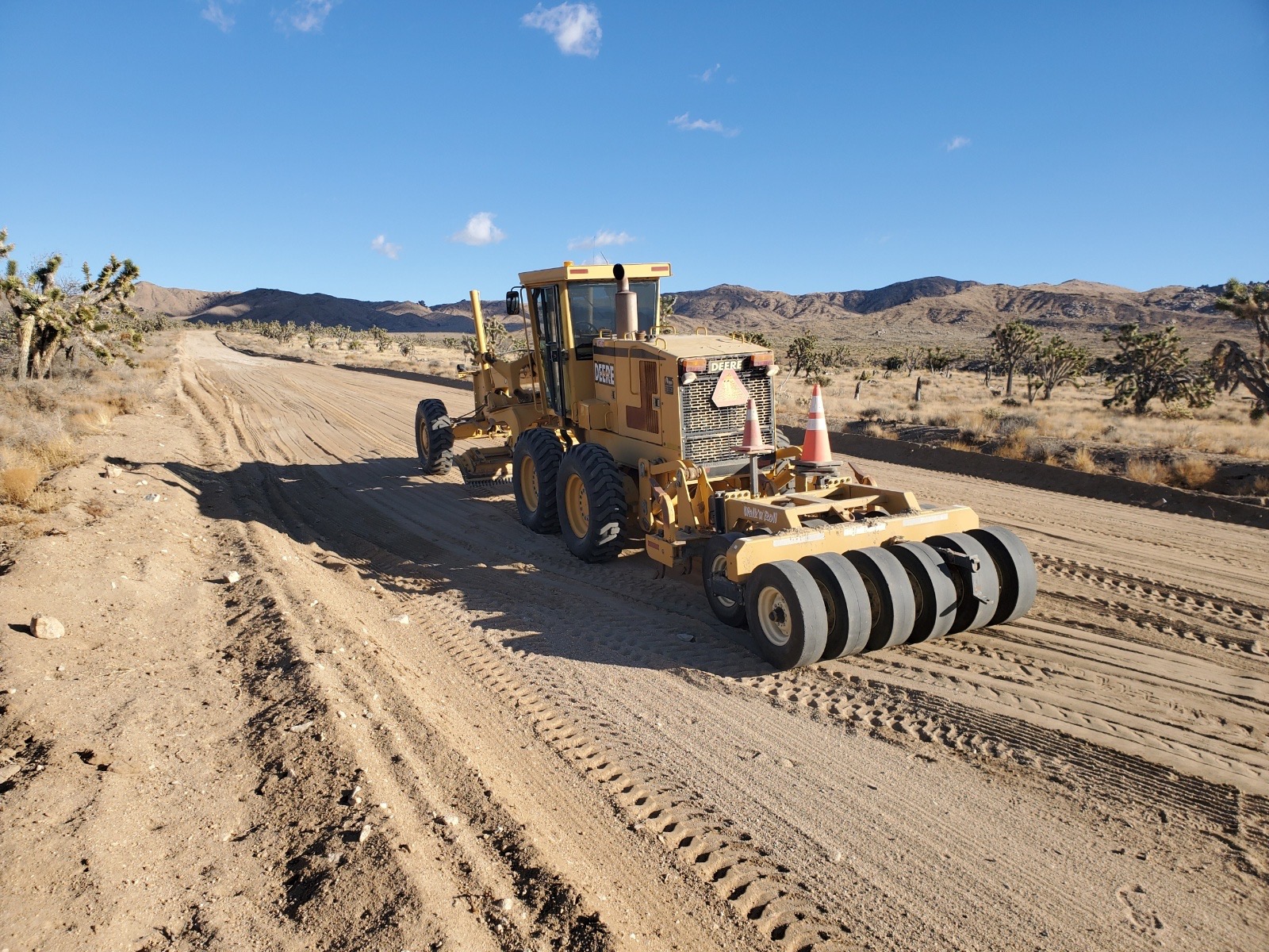 Road Grader A road grader on a diret road in the Mojave desert