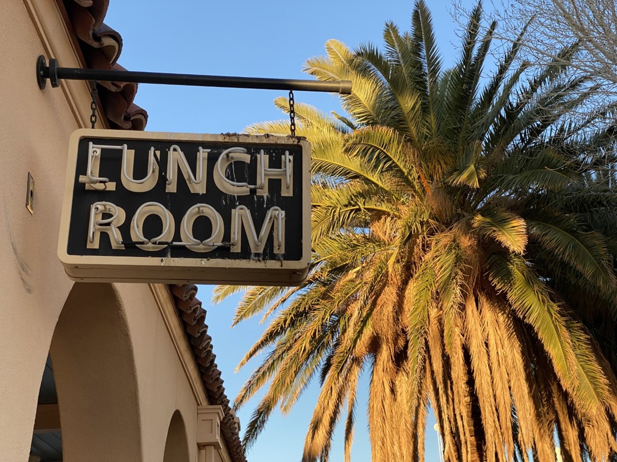 The historic Lunch Room sign at Kelso Depot backdropped by a palm tree