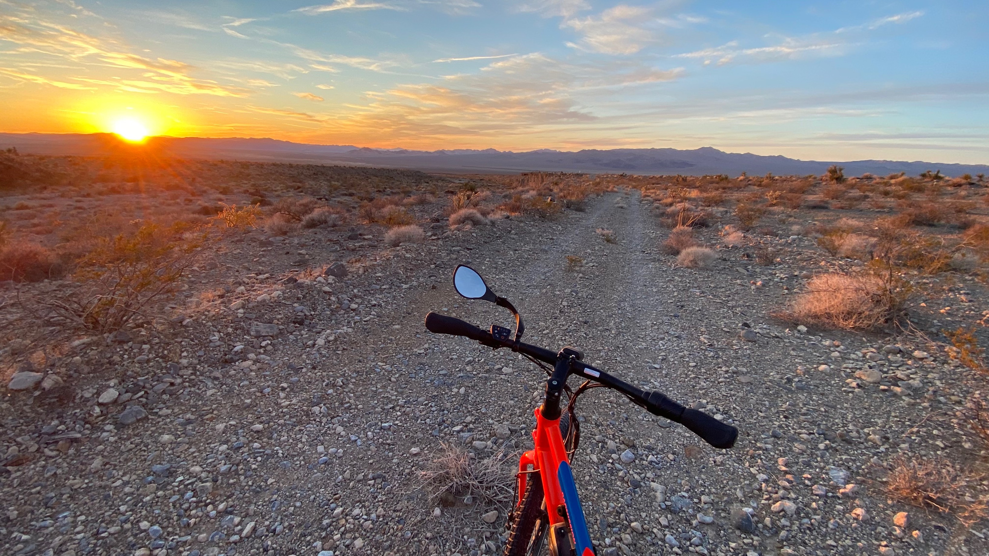 a red bike on a dirt road at sunset