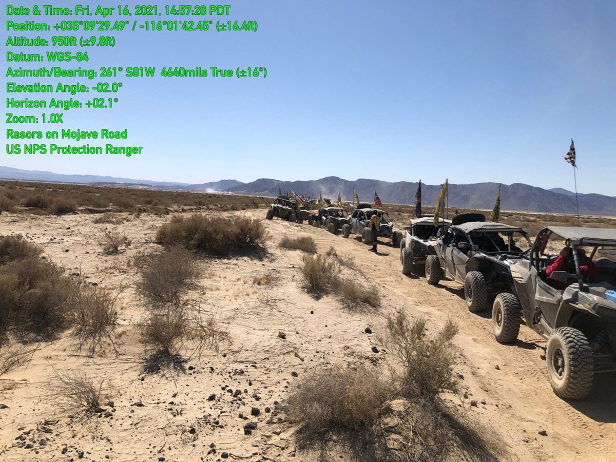 A long caravan of razors illegally on the Mojave Road.  Creosote and Mountains in background.