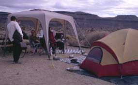 Campers with an easy up and tent with bluffs in the background.