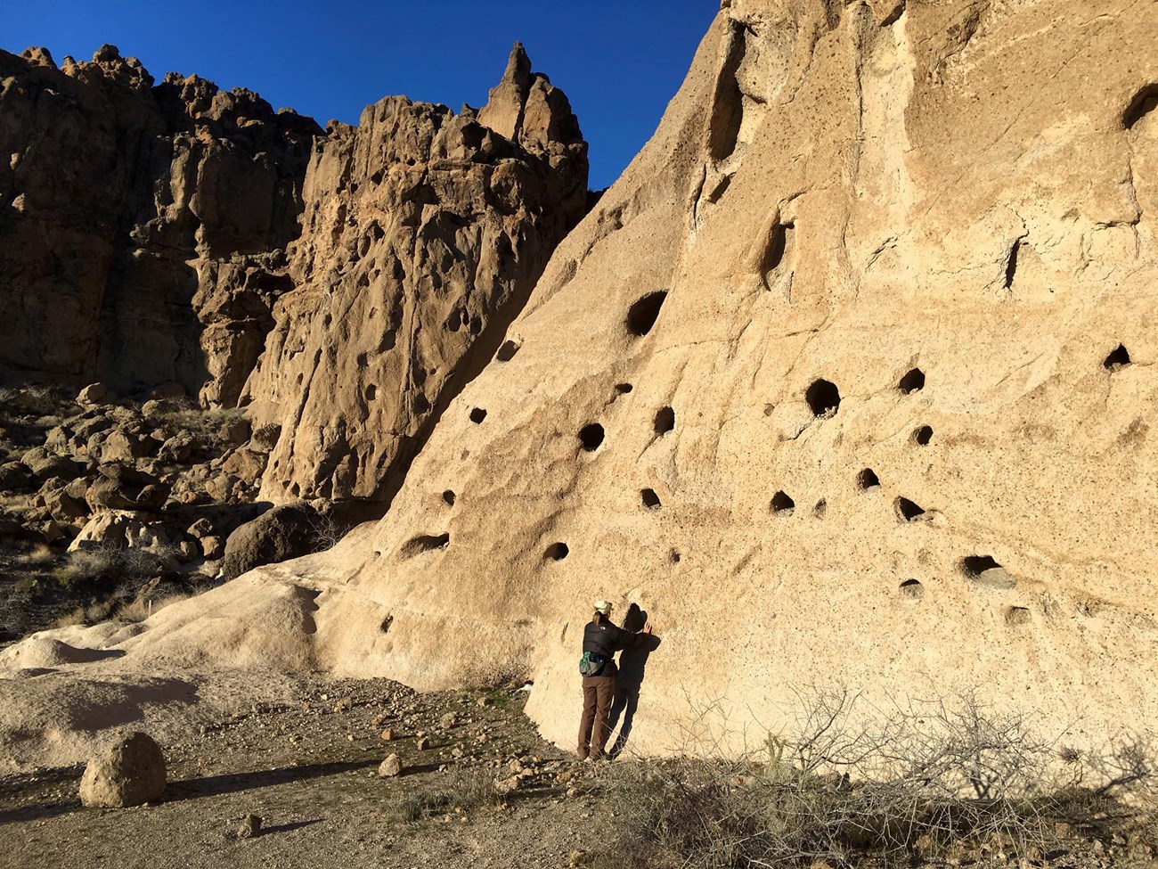 a hiker at hole ridden rock face