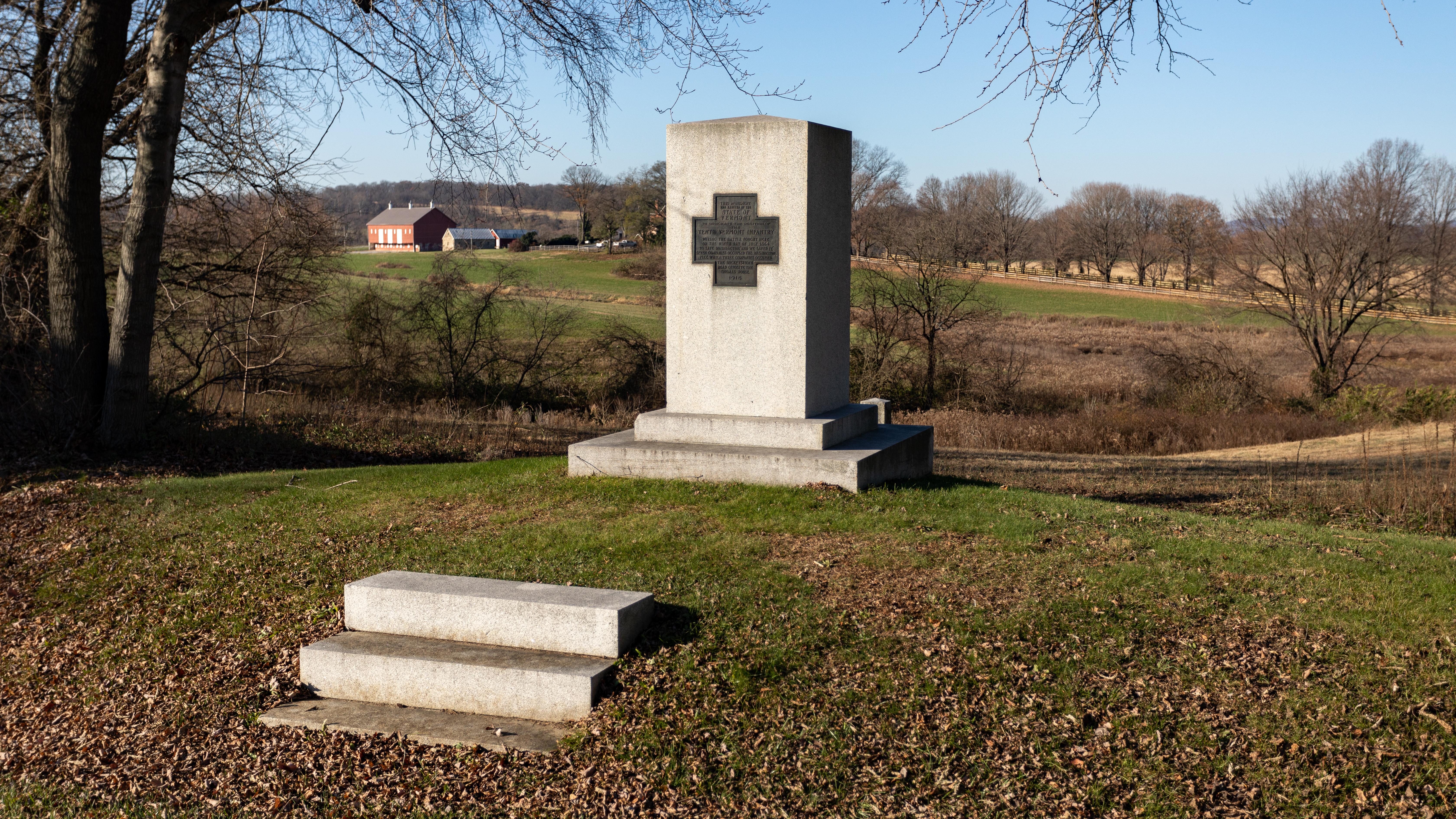 Stone memorial with rolling green farmland in the background.