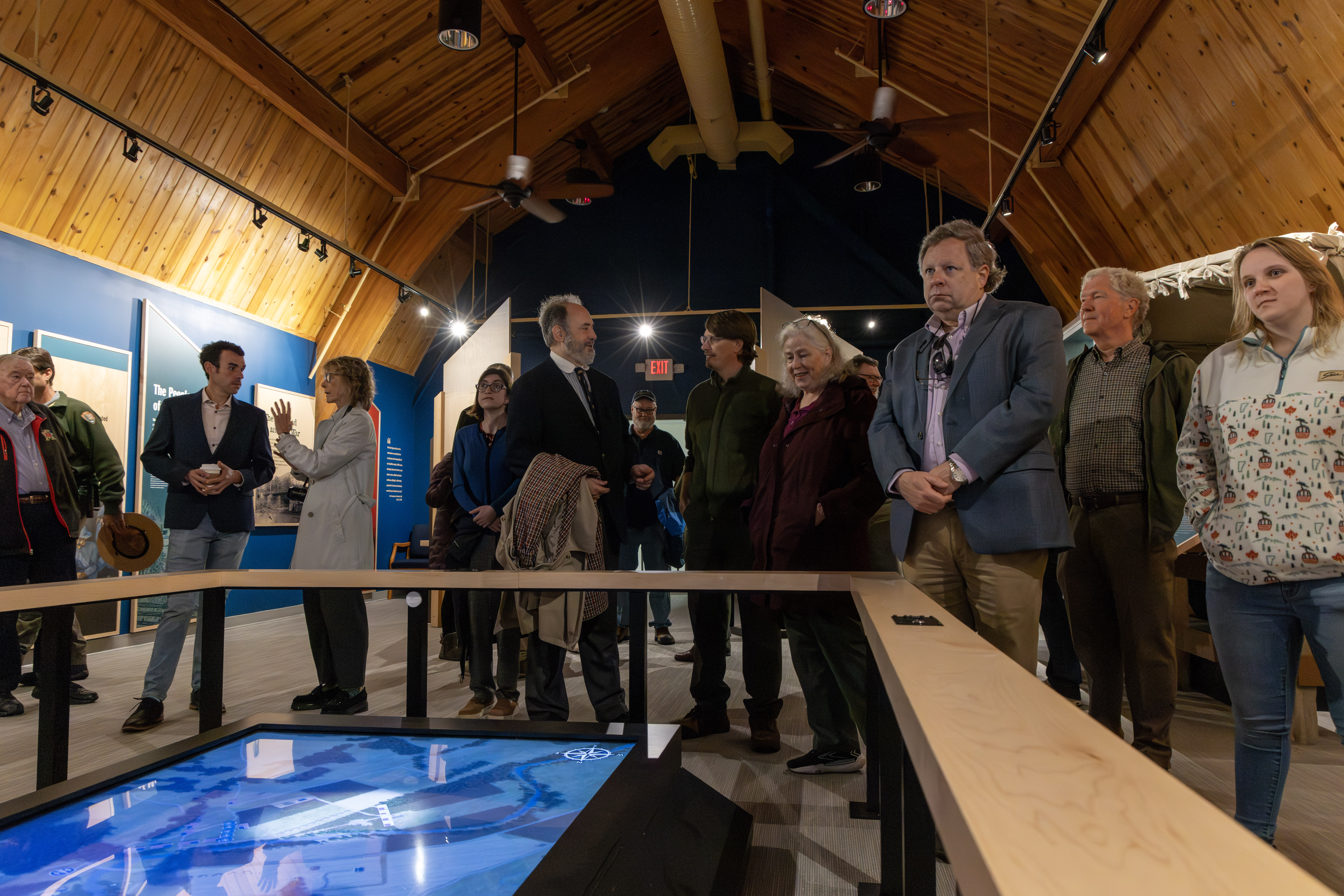 Group of people talk and look up at a museum exhibit.