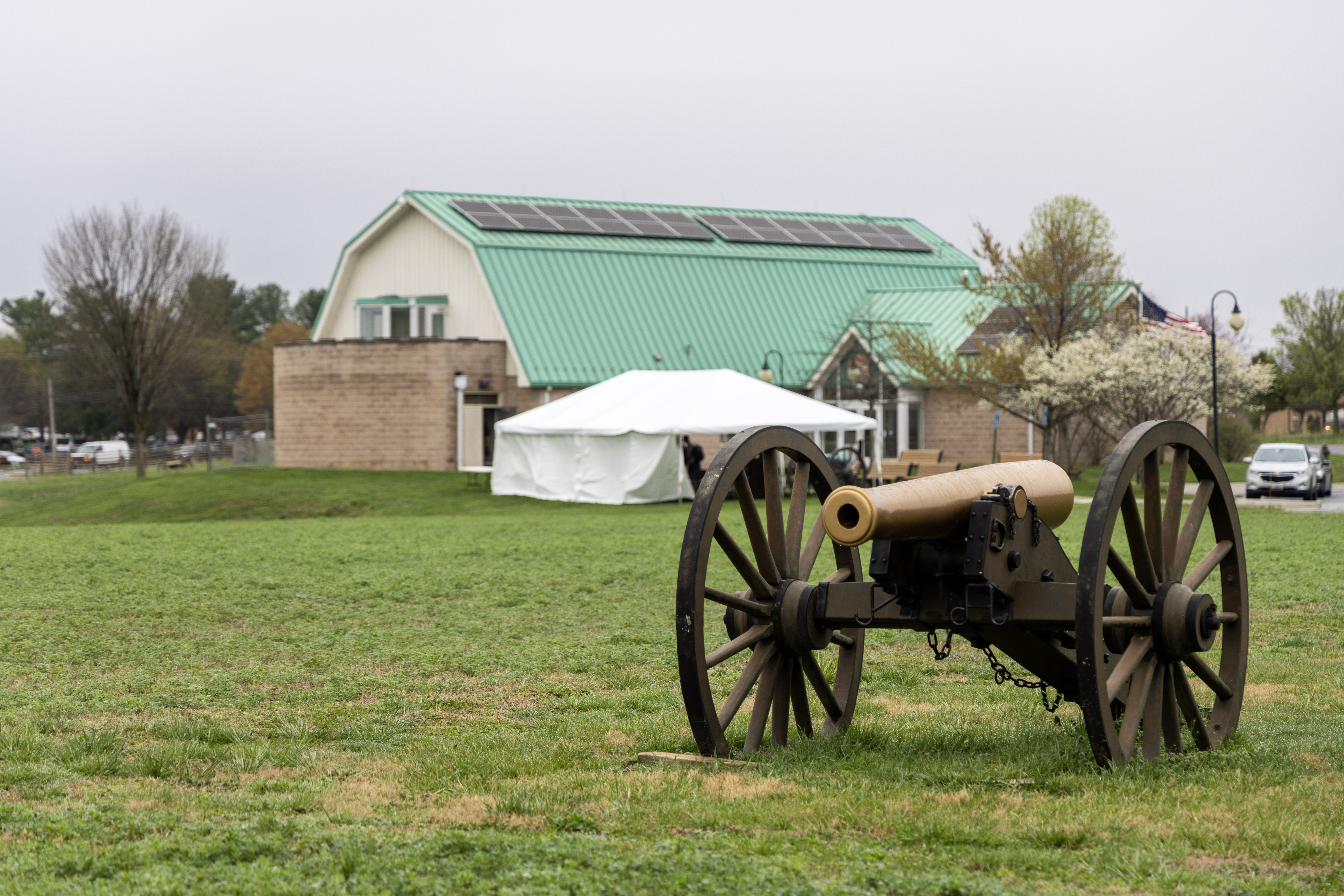 Cannon positioned on a grassy field with a park building in the background