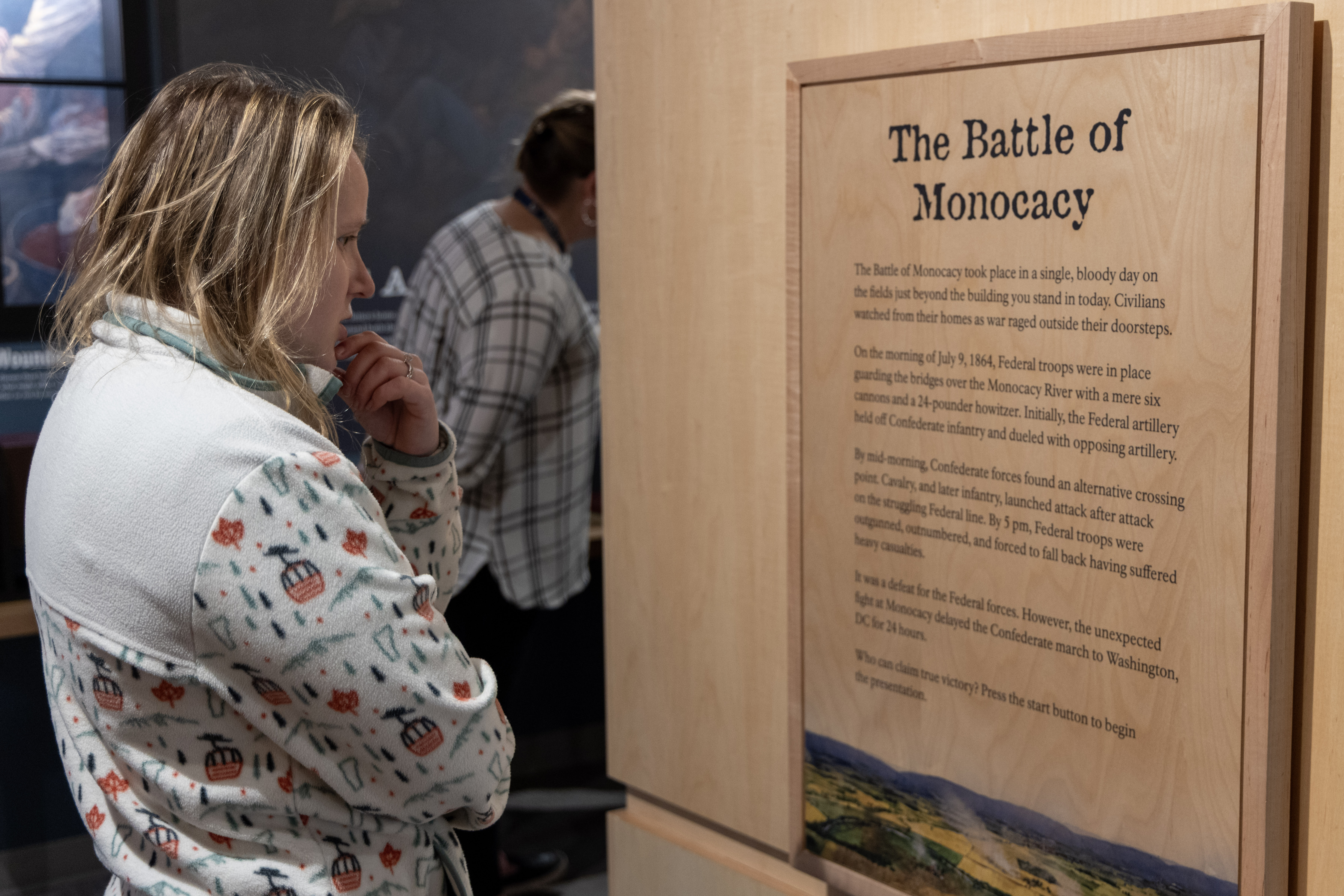A visitor stands and reads an exhibit panel about the Battle of Monocacy.