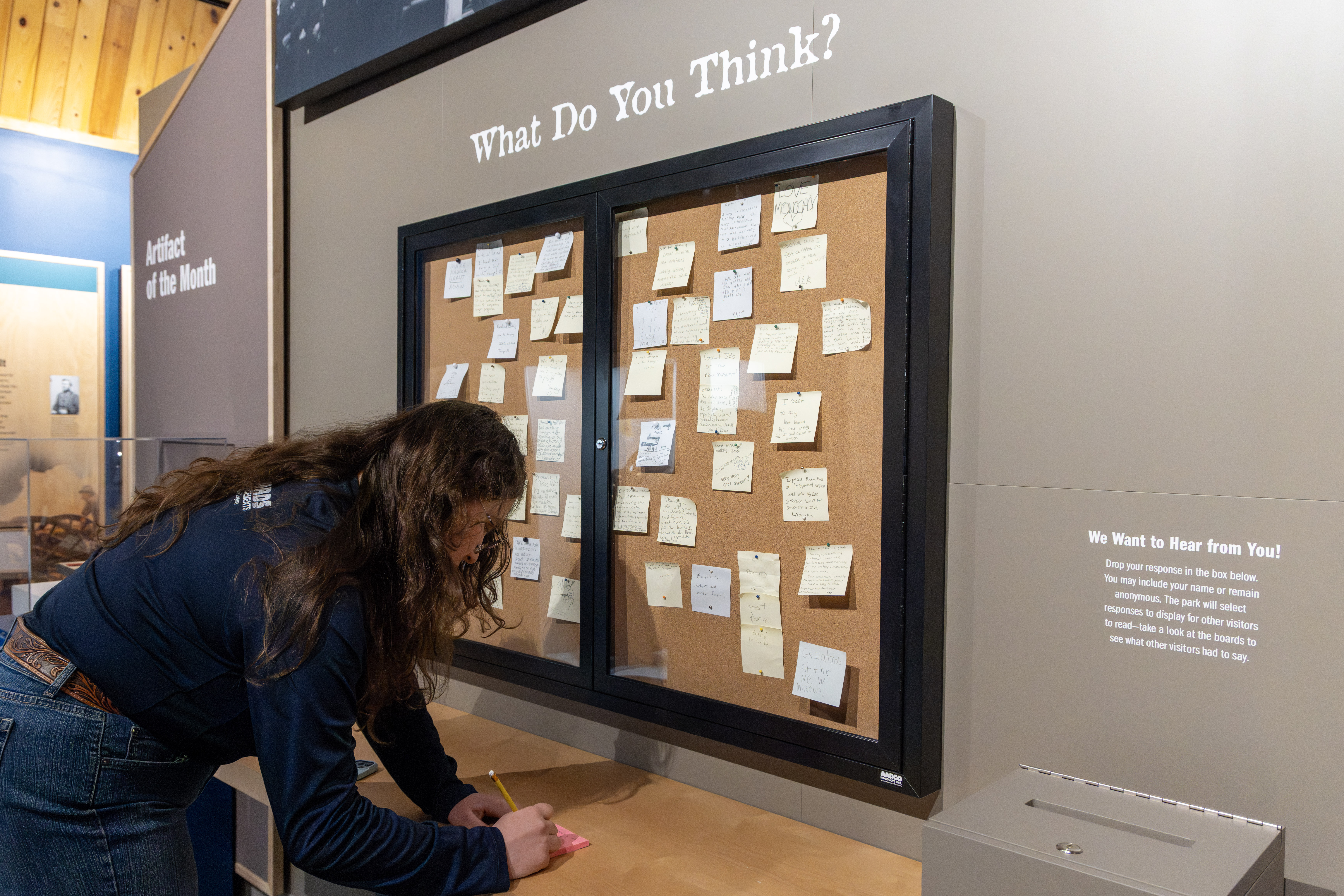 A visitor writes a response to a museum's interactive prompt.
