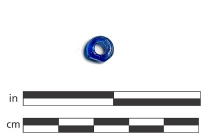 A small blue glass bead shown with a scale.