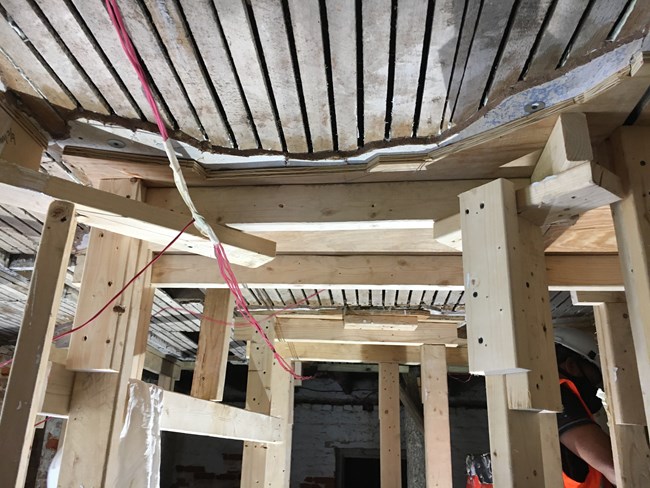 Wood bracing presses pieces of plaster tight to the wood lathe in the ceiling.