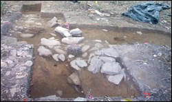 An archeological dig reveals stone foundations.