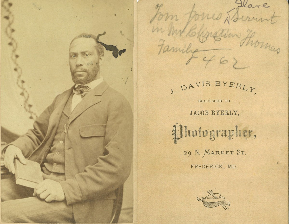 Front and back of a 1870s Carte de Visite: A black man wearing a suit, seated holding a book. Back: Handwritten at top: Tom Jones, slave/servant in Mr. Christian Thomas Family 462.
