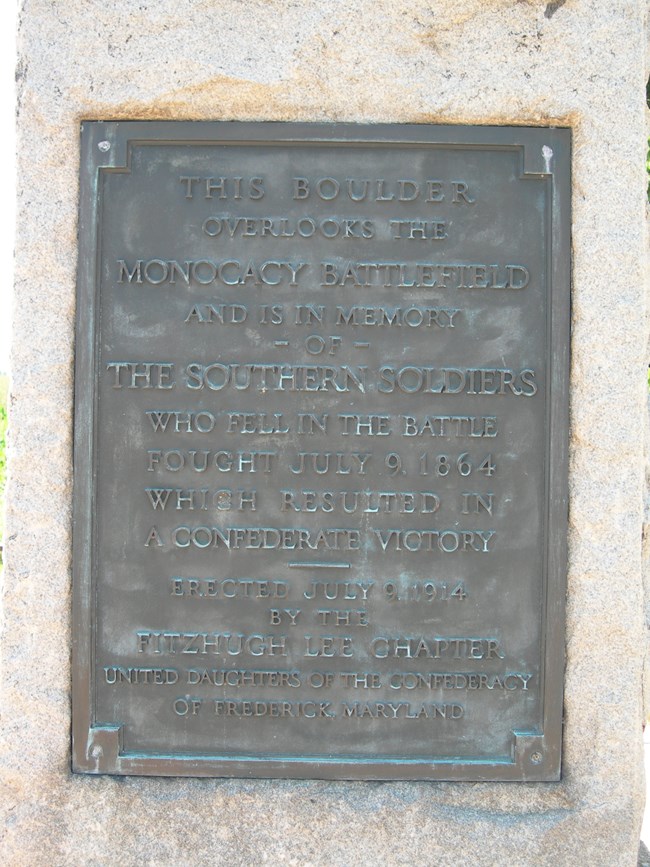 A close up photo of a bronze plaque with writing on it.